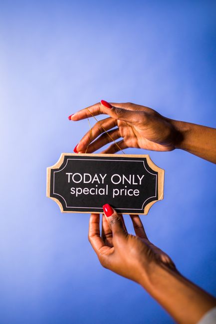A pair of hands with neatly manicured nails and red nail polish are holding a small rectangular sign with a black background, a decorative beige border, and white text that reads 'TODAY ONLY special p
